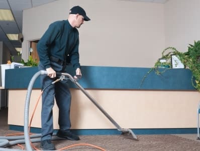 Mitarbeiter von Bavaria Cleaning staugt im Zuge der Unterhaltsreinigung den Empfangsbereich einer Firma